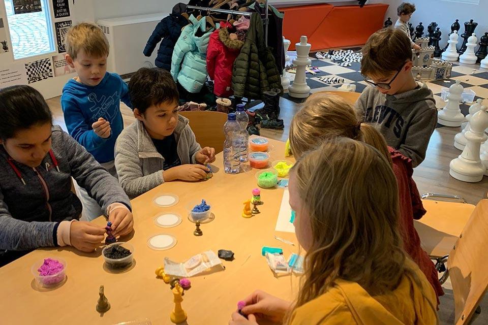 Boys and girls forming chess pieces from colored dough