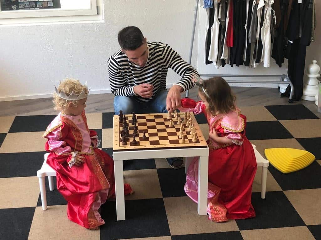 Two little girls dressed as princesses playing chess