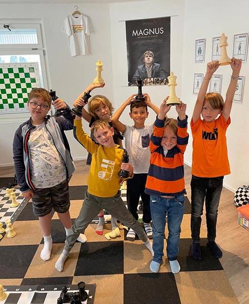 Children raising chess pieces above their heads