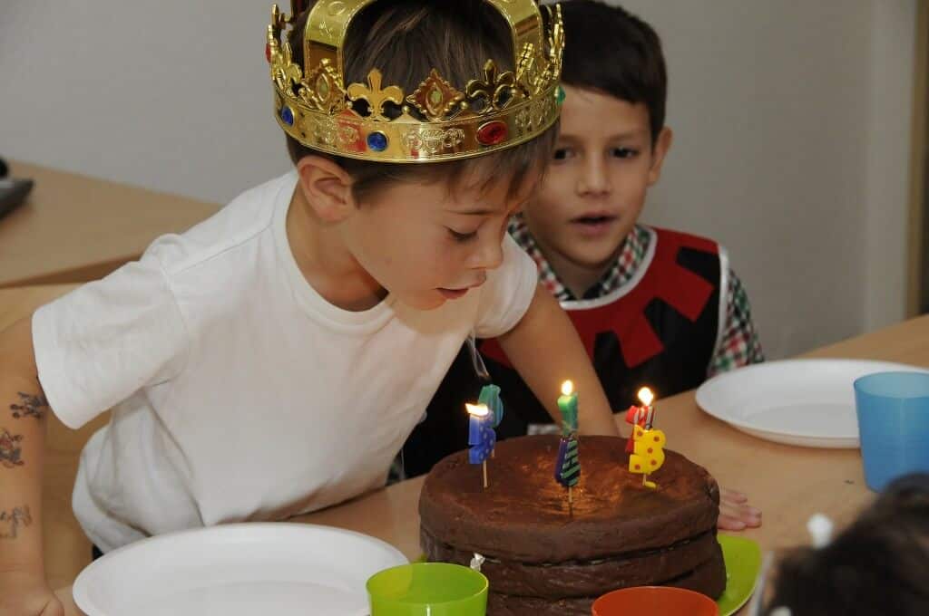 Ein kleiner Schachkönig bläst die Kerzen seiner Geburtstagsparty - Torte aus