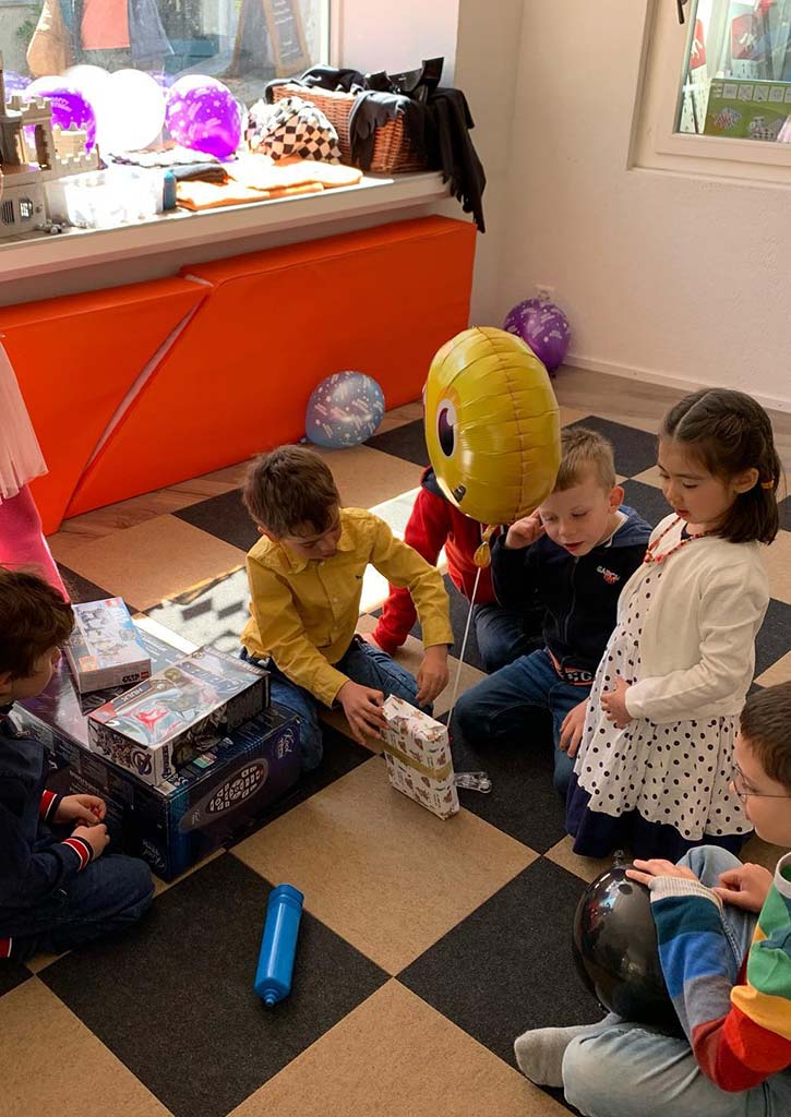 Gruppe von Kindern packt Geburtstagsgeschenke aus
