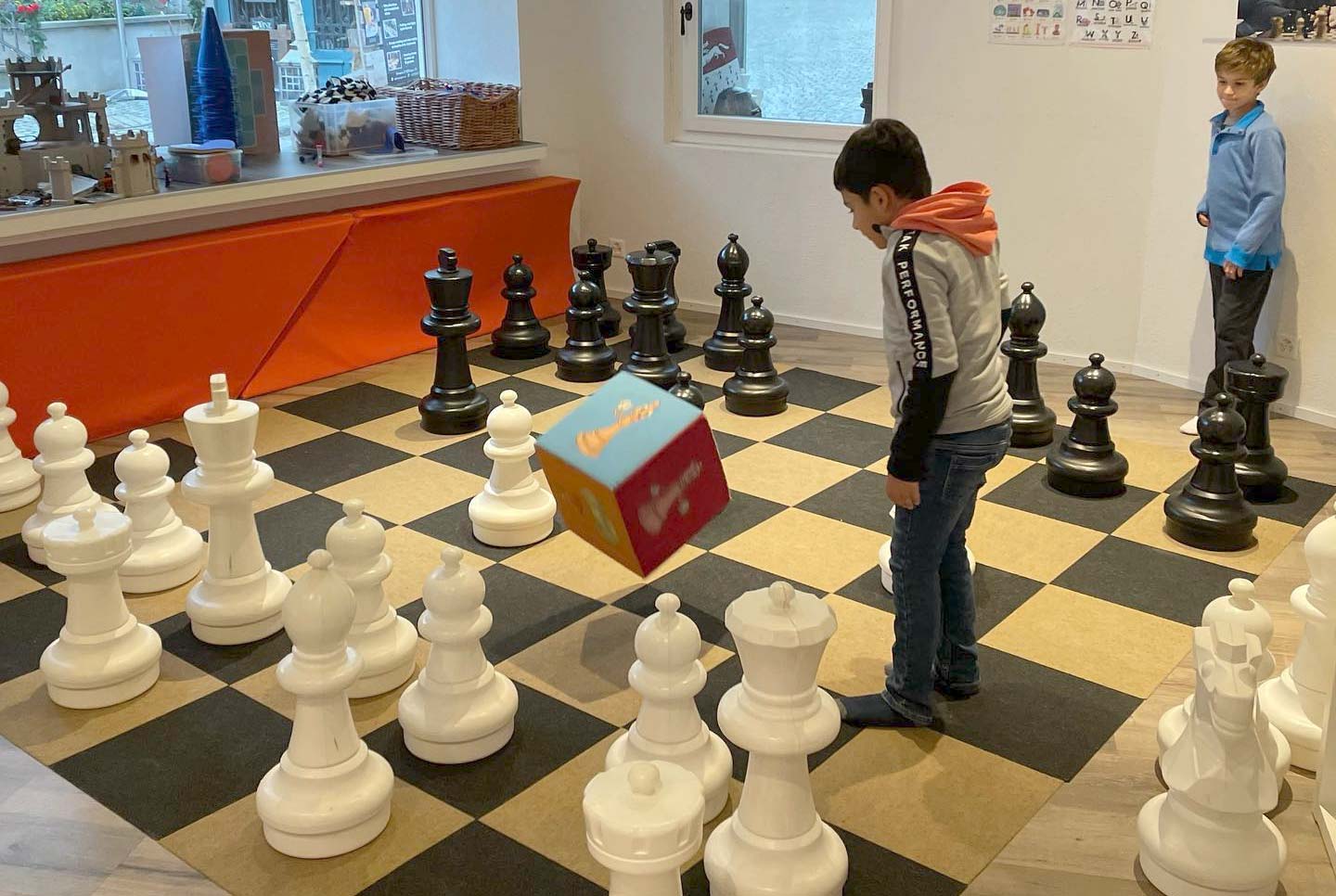 Kinder spielen Würfelschach in einem Chess4Kids Kursraum