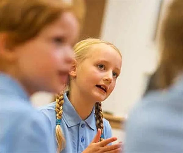 Girl discussing with other pupils in class